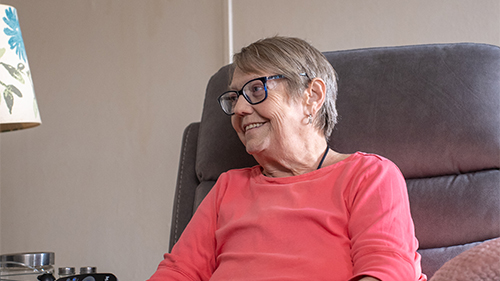 Older woman, Sandy Drakes, smiling while sitting in a lounging chair.